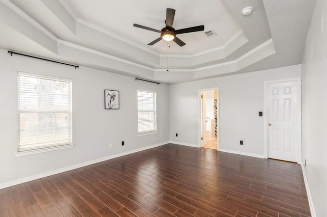 spare room with dark wood-type flooring, crown molding, and a raised ceiling