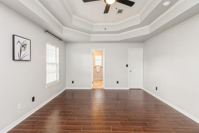 unfurnished bedroom featuring ornamental molding, connected bathroom, dark hardwood / wood-style flooring, and a tray ceiling