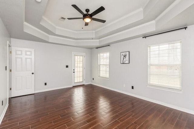 empty room with a raised ceiling, ceiling fan, ornamental molding, and dark hardwood / wood-style flooring