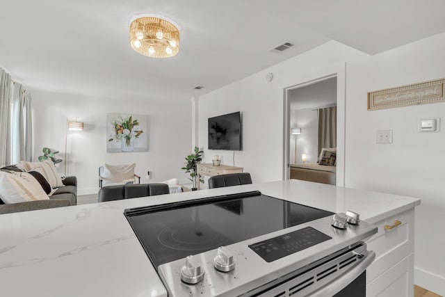 kitchen with light stone counters, stainless steel electric range, and white cabinets