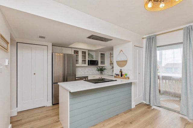 kitchen featuring stainless steel fridge, backsplash, white cabinets, light hardwood / wood-style floors, and kitchen peninsula