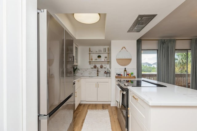 kitchen with sink, light hardwood / wood-style flooring, stainless steel appliances, light stone counters, and white cabinets