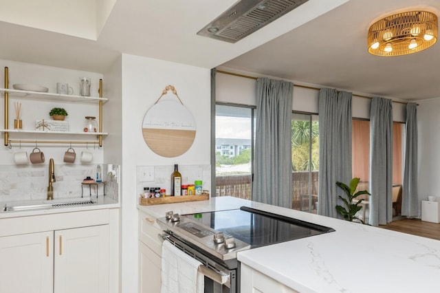 kitchen with sink, white cabinetry, stainless steel electric stove, light stone countertops, and decorative backsplash