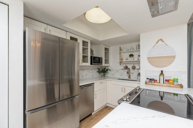 kitchen featuring sink, appliances with stainless steel finishes, backsplash, light stone counters, and white cabinets