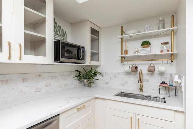 kitchen featuring sink, white cabinets, decorative backsplash, light stone counters, and stainless steel appliances