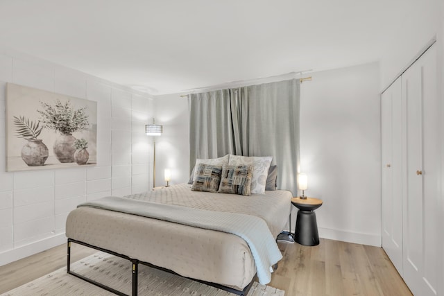 bedroom with tile walls, light hardwood / wood-style flooring, and a closet