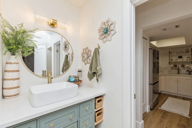 bathroom featuring hardwood / wood-style flooring, vanity, and tasteful backsplash