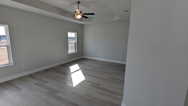 unfurnished room with ceiling fan, a raised ceiling, and light hardwood / wood-style floors