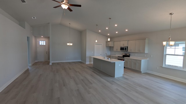 kitchen with stainless steel appliances, a center island with sink, light wood-type flooring, and decorative light fixtures