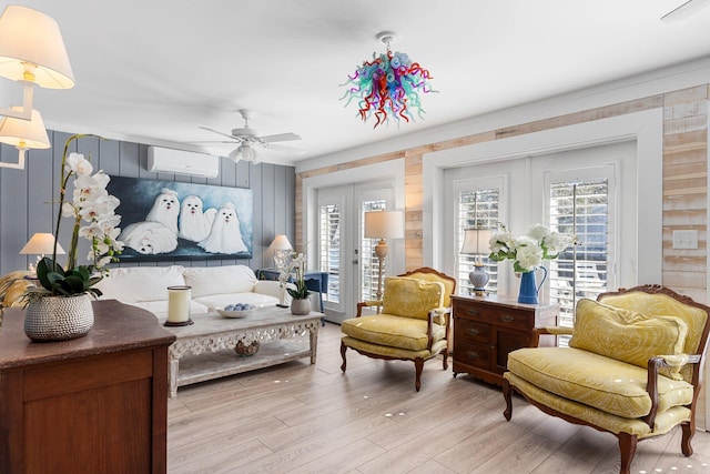 living area featuring light hardwood / wood-style flooring, a wealth of natural light, a wall unit AC, and french doors