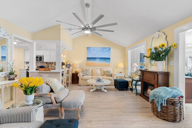 living room with ceiling fan, vaulted ceiling, and light hardwood / wood-style floors