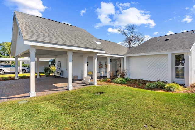 rear view of house featuring a carport and a lawn