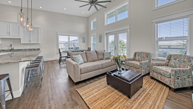 living room with a high ceiling, dark wood-type flooring, and ceiling fan