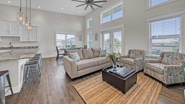 living room featuring a high ceiling, dark wood-type flooring, and ceiling fan