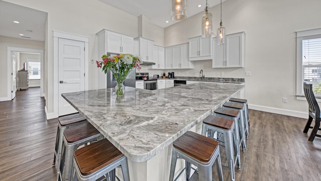 kitchen featuring white cabinetry, appliances with stainless steel finishes, a large island, and a breakfast bar