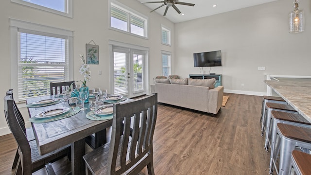 dining space featuring a towering ceiling, dark hardwood / wood-style floors, ceiling fan, and french doors