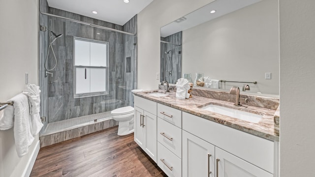 bathroom with vanity, a shower with shower door, hardwood / wood-style floors, and toilet