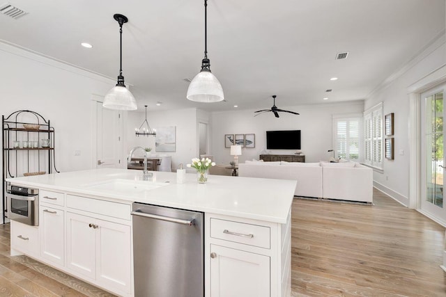 kitchen with sink, a center island with sink, hanging light fixtures, appliances with stainless steel finishes, and white cabinets