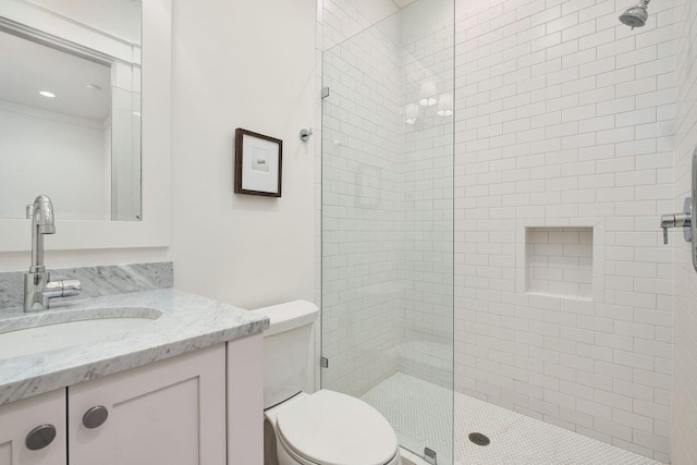 bathroom featuring vanity, tiled shower, and toilet