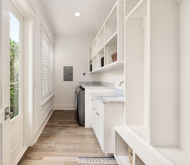 laundry area with sink, cabinets, light hardwood / wood-style flooring, ornamental molding, and electric panel