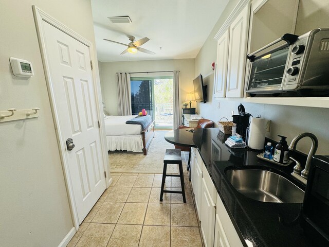 kitchen featuring white cabinetry, ceiling fan, light tile patterned flooring, and sink