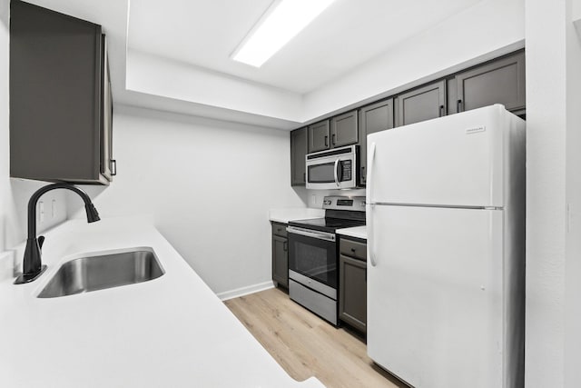 kitchen featuring stainless steel appliances, sink, and light hardwood / wood-style flooring