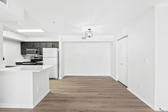 kitchen featuring appliances with stainless steel finishes, sink, kitchen peninsula, and hardwood / wood-style floors