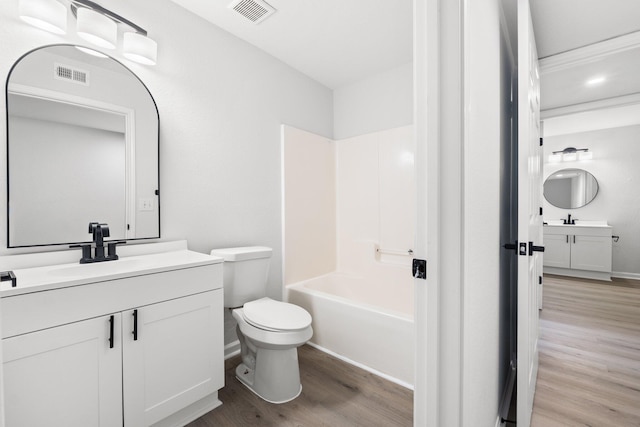 full bathroom featuring wood-type flooring, vanity, washtub / shower combination, and toilet