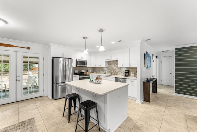 kitchen featuring french doors, light tile patterned floors, appliances with stainless steel finishes, pendant lighting, and white cabinets