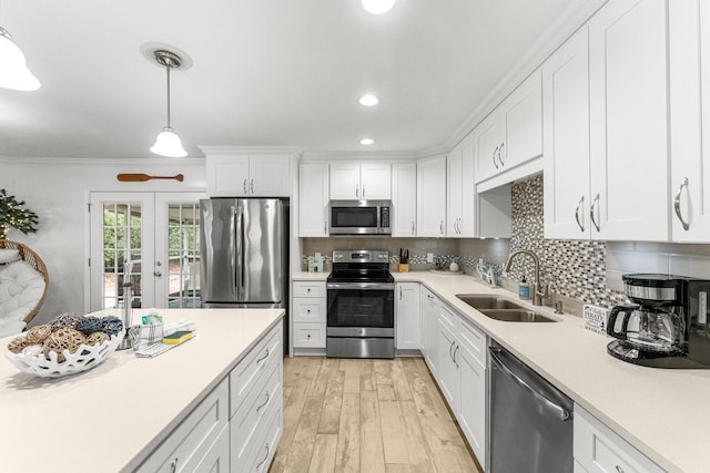 kitchen featuring pendant lighting, sink, appliances with stainless steel finishes, white cabinets, and french doors