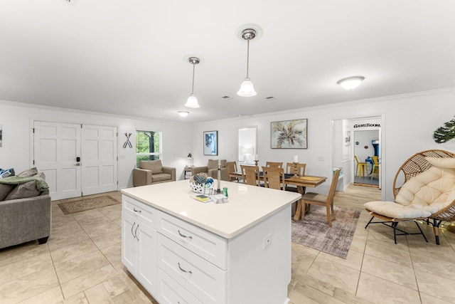 kitchen featuring pendant lighting, white cabinetry, a center island, light tile patterned floors, and crown molding