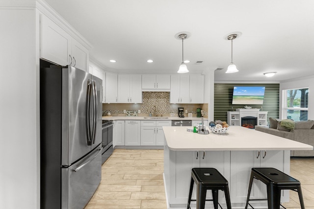 kitchen with sink, a breakfast bar area, appliances with stainless steel finishes, white cabinets, and decorative light fixtures