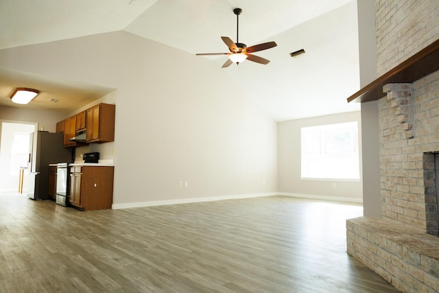 unfurnished living room featuring hardwood / wood-style flooring, ceiling fan, vaulted ceiling, and a brick fireplace