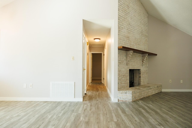 unfurnished living room with high vaulted ceiling, a fireplace, and light hardwood / wood-style floors