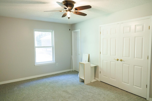 unfurnished bedroom featuring ceiling fan, light colored carpet, a closet, and a textured ceiling