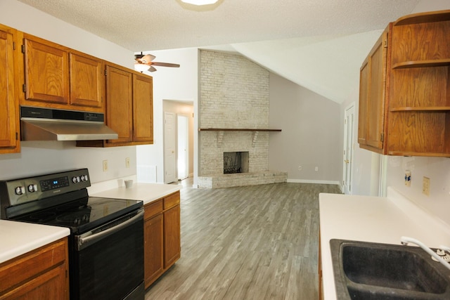 kitchen with lofted ceiling, sink, a brick fireplace, light hardwood / wood-style flooring, and black range with electric cooktop