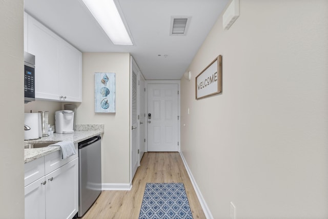 laundry area featuring sink and light hardwood / wood-style flooring