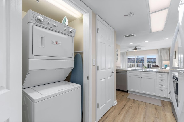 laundry room with ceiling fan, stacked washer / dryer, sink, and light hardwood / wood-style flooring