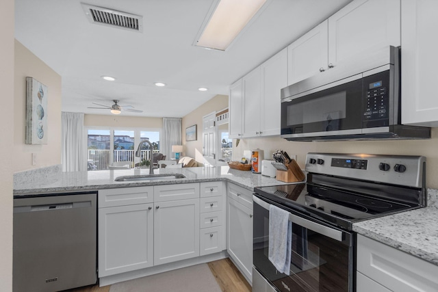 kitchen with white cabinetry, sink, light stone counters, kitchen peninsula, and stainless steel appliances