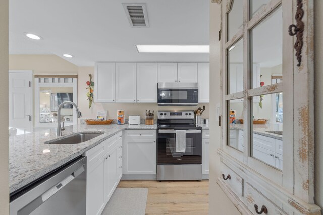 kitchen featuring white cabinetry, sink, light stone counters, and appliances with stainless steel finishes