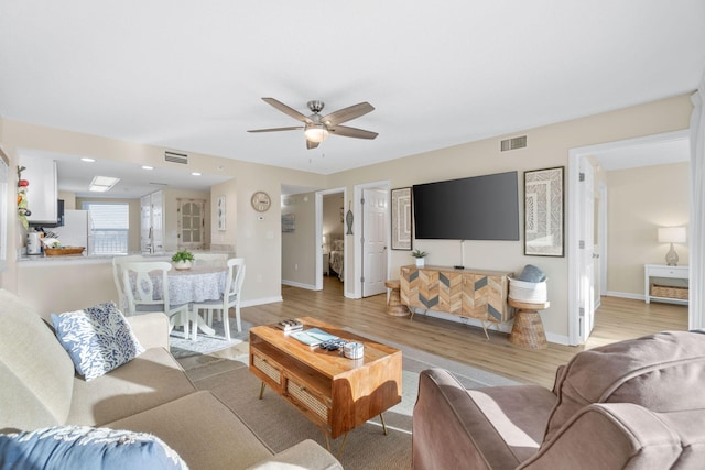 living room featuring ceiling fan, sink, and light hardwood / wood-style floors