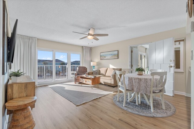 living room featuring a textured ceiling, light hardwood / wood-style floors, and ceiling fan