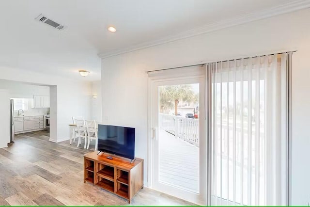 living room featuring sink, crown molding, and light hardwood / wood-style floors