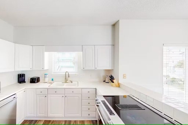 kitchen featuring stainless steel appliances, sink, white cabinets, and light hardwood / wood-style floors