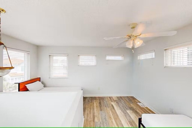 bedroom featuring multiple windows, ceiling fan, and light wood-type flooring