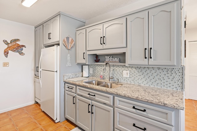 kitchen with sink, gray cabinetry, backsplash, white fridge, and light tile patterned floors