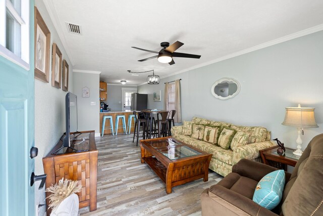 living room with ceiling fan, ornamental molding, and light hardwood / wood-style floors