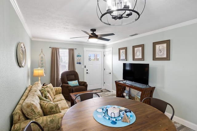 dining area with ornamental molding, ceiling fan with notable chandelier, and a textured ceiling