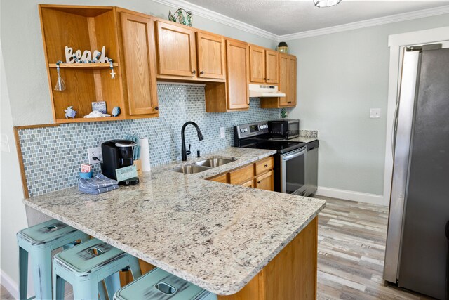 kitchen with light stone countertops, appliances with stainless steel finishes, sink, and kitchen peninsula