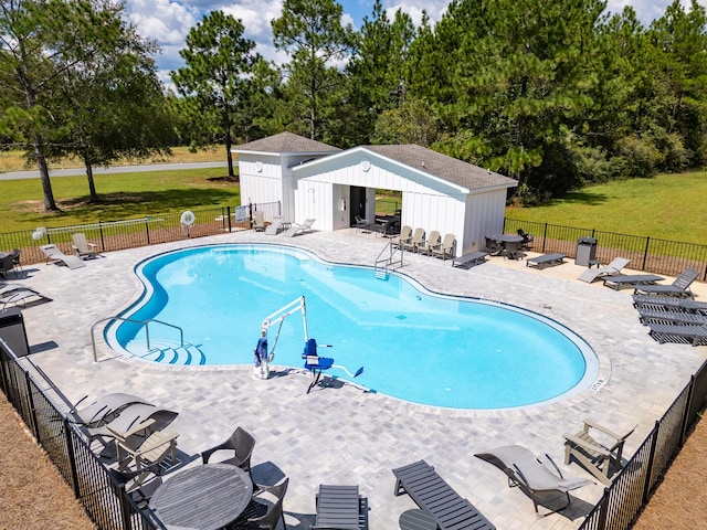 pool featuring an outbuilding, a patio, a yard, and fence